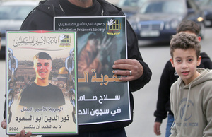 A Palestinian man holds pictures of Palestinian prisoners during the solidarity vigil in front of the International Committee of the Red Cross in Nablus, West Bank. The vigil also served as a protest against the death penalty law approved by the Israeli cabinet.