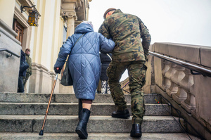A soldier helps an elderly woman up stairs to the church. On the afternoon of the 14th of February, Poland celebrates the National Day of Remembrance of the Home Army Soldiers, a state holiday commemorating the Polish underground militias during World War II. After a Mass for the fallen at the Basilica of the Holy Cross, a Parade of Respect passes through the streets of Warsaw in the direction of the Monument to the Polish Underground State and the Home Army at the Polish Parliament, where a wreath-laying ceremony takes place.
