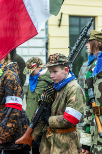 A young boy in period military dress carries a large machine gun. On the afternoon of the 14th of February, Poland celebrates the National Day of Remembrance of the Home Army Soldiers, a state holiday commemorating the Polish underground militias during World War II. After a Mass for the fallen at the Basilica of the Holy Cross, a Parade of Respect passes through the streets of Warsaw in the direction of the Monument to the Polish Underground State and the Home Army at the Polish Parliament, where a wreath-laying ceremony takes place.