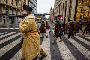 Historical reenactors in period military dress cross a street. On the afternoon of the 14th of February, Poland celebrates the National Day of Remembrance of the Home Army Soldiers, a state holiday commemorating the Polish underground militias during World War II. After a Mass for the fallen at the Basilica of the Holy Cross, a Parade of Respect passes through the streets of Warsaw in the direction of the Monument to the Polish Underground State and the Home Army at the Polish Parliament, where a wreath-laying ceremony takes place.
