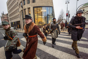 Historical reenactors in period military dress cross a street. On the afternoon of the 14th of February, Poland celebrates the National Day of Remembrance of the Home Army Soldiers, a state holiday commemorating the Polish underground militias during World War II. After a Mass for the fallen at the Basilica of the Holy Cross, a Parade of Respect passes through the streets of Warsaw in the direction of the Monument to the Polish Underground State and the Home Army at the Polish Parliament, where a wreath-laying ceremony takes place.