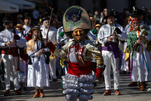 A man dressed in white, with a mask and a large hat, carries a whip. during the 1st Masquerade Parade through the center of Madrid, organized by the regional associations of Asturias, Galicia, and Zamora, the heart of the Spanish capital was transformed into a stage for ancestral rites from the Spanish regions of Asturias, Galicia, and Zamora.