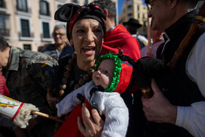 A woman in a colorful costume carries a doll in her arms, simulating a baby. during the 1st Masquerade Parade through the center of Madrid, organized by the regional associations of Asturias, Galicia, and Zamora, the heart of the Spanish capital was transformed into a stage for ancestral rites from the Spanish regions of Asturias, Galicia, and Zamora.