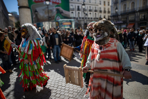 A couple dressed in colorful costumes and masks is seen. during the 1st Masquerade Parade through the center of Madrid, organized by the regional associations of Asturias, Galicia, and Zamora, the heart of the Spanish capital was transformed into a stage for ancestral rites from the Spanish regions of Asturias, Galicia, and Zamora.