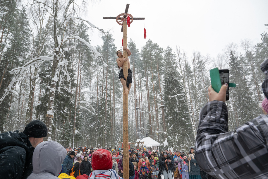 A man climbs a pole to retrieve a prize, a traditional festive activity, during celebrations of Maslenitsa (Shrovetide), a traditional Russian folk festival marking the end of winter, at Emerald Lake in the village of Toksovo in the Leningrad region.