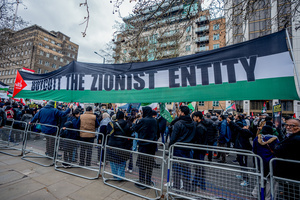Huge pro-Iranian regime banner calling for the boycotting of Israel. Many thousands congregated in Central London in an international demonstration of support for Palestinian rights. They were separated by Police from pro-Israeli and anti-Iranian-regime counter-protestors who met on the opposite side of the River Thames after the rally was banned from marching by the Home Secretary Shabana Mahmood. Rapper Bob Vylan spoke at the rally and is currently being investigated for chanting “Death to the IDF”.