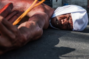 A devotee seen laying down in the street as part of self-flagellation on April 3, 2026, as an act of symbolic participation in the suffering of Jesus Christ. The Catholic Church maintains that physical sacrifice is unnecessary for the forgiveness of sins, many local flagellants continue the grueling practice as a public display of faith, endurance, and communal identity.