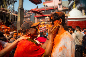 The reveler smears the vermilion powder at a colleague during the Festival. Sindoor Jatra or vermillion powder festival is celebrated each year to welcome the start of spring and Nepalese New Year, by playing a traditional instrument, singing, dancing, and carrying chariots of several gods and goddesses around the place.