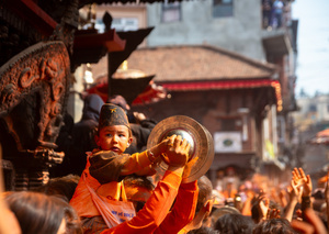 A kid plays traditional musical instruments during the Festival. Sindoor Jatra or vermillion powder festival is celebrated each year to welcome the start of spring and Nepalese New Year, by playing a traditional instrument, singing, dancing, and carrying chariots of several gods and goddesses around the place.