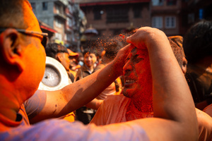 The reveler smears the vermilion powder at a colleague during the Festival. Sindoor Jatra or vermillion powder festival is celebrated each year to welcome the start of spring and Nepalese New Year, by playing a traditional instrument, singing, dancing, and carrying chariots of several gods and goddesses around the place.