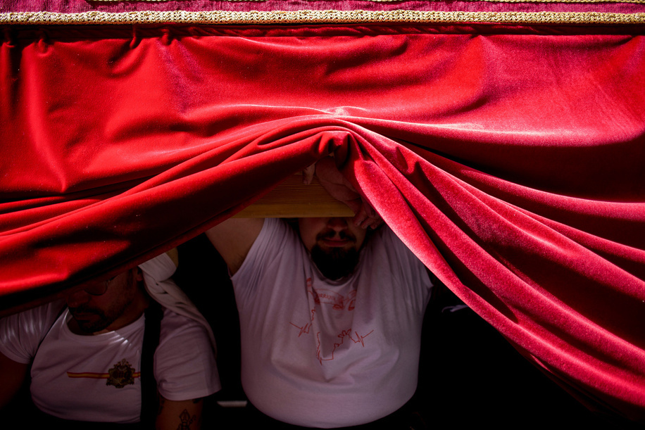 A member of the Brotherhood of Jesus of Love rests on the wooden platform during the procession of the image of Our Father Jesus of Love (La Borriquita). This procession inaugurates Holy Week in Madrid.