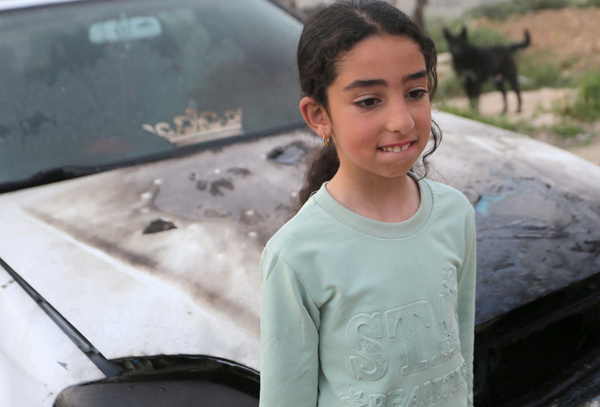 A Palestinian girl stands in front of her burning car after an attack by a group of Jewish settlers on the village of Asira al-Qibliya, south of Nablus in the West Bank. Local residents reported that the settlers torched two cars and a house, uprooted olive trees, and threw stones at Palestinian vehicles.