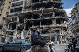 Traffic passes a destroyed row of businesses in Beirut’s southern suburbs, known as Dahieyh, during a 10-day ceasefire between Israel and Hezbollah. After a 10-day ceasefire declared on April 16, 2026, displaced families in Lebanon began returning to assess widespread destruction from weeks of fighting that killed over 2,400 people. Many homes, hospitals, and key infrastructure were damaged, while more than one million people remain displaced. Despite the pause, access to some areas is restricted, and fears persist that fighting could resume.