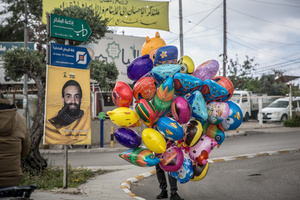 A boy sells balloons beside a picture of a fighter in the Saida District, during a 10-day ceasefire between Israel and Hezbollah. Many displaced people used the opportunity to check on their homes. After a 10-day ceasefire declared on April 16, 2026, displaced families in Lebanon began returning to assess widespread destruction from weeks of fighting that killed over 2,400 people. Many homes, hospitals, and key infrastructure were damaged, while more than one million people remain displaced. Despite the pause, access to some areas is restricted, and fears persist that fighting could resume.
