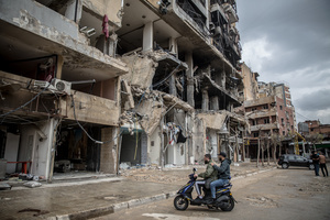 Young men on a motorbike in front of a row of destroyed businesses in Beirut’s southern suburbs, known as Dahieyh, are pictured during a 10-day ceasefire between Israel and Hezbollah. Many displaced people used the opportunity to check on their homes. After a 10-day ceasefire declared on April 16, 2026, displaced families in Lebanon began returning to assess widespread destruction from weeks of fighting that killed over 2,400 people. Many homes, hospitals, and key infrastructure were damaged, while more than one million people remain displaced. Despite the pause, access to some areas is restricted, and fears persist that fighting could resume.