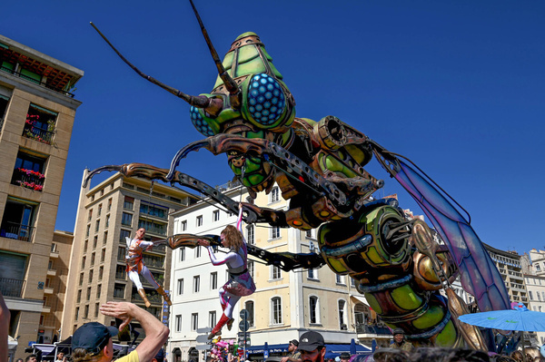 A decorative float depicting a large, artistic insect sculpture is seen during the carnival. The 36th Marseille Carnival transformed the historic Old Port into a vibrant celebration under the theme “Kingdom of Extravaganza.” Thousands of residents and visitors gathered to watch a parade of quirky characters and oversized floats moving from the Théâtre de la Criée to a musical finale at City Hall. The annual event showcased Marseille’s creative spirit with face-painting workshops, marching bands, and costumes designed by local community groups.