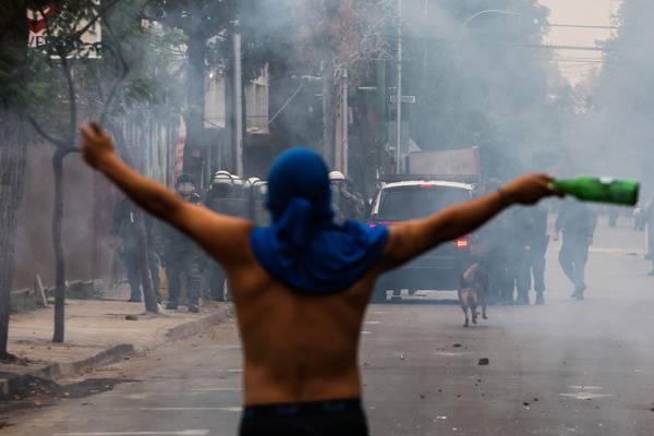 A protester raises his arms against the police during a march for Labor Day. Hundreds of people marched for Labor Day, May 1st, in the city of Santiago, Chile.