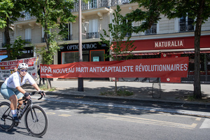 A biker pass by a New Revolutionary Anti-capitalist Party banner on the Boulevard Voltaire during the May Day celebration in Paris. Tens of thousands of trade unionists and grassroots activists gathered in Paris to celebrate the achievements of the labor movement and raise awareness of workers’ rights.