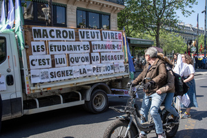 A cyclist couple read the message on the side of the van during the May Day celebration in Paris. The message says: "Macron wants to expel foreign students; he's the one who's going to get rid of. Sign the petition." Tens of thousands of trade unionists and grassroots activists gathered in Paris to celebrate the achievements of the labor movement and raise awareness of workers’ rights.