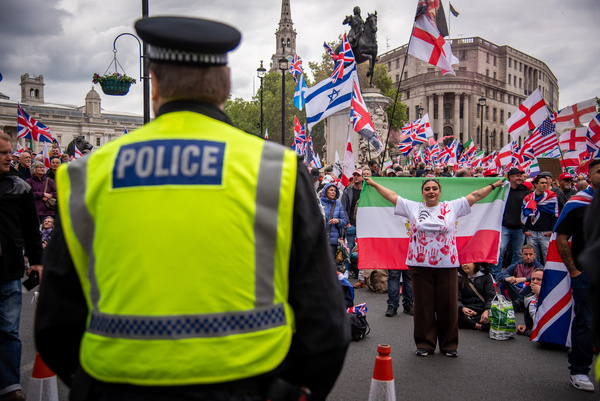 A protestor holds a large Iranian flag during the Unite the Kingdom March. Tommy Robinson tried to use his protest to silence solidarity with Palestine and divide communities through racism and islamophobia, people stood together to defend the right to protest and to say clearly that the far right do not speak for the majority.