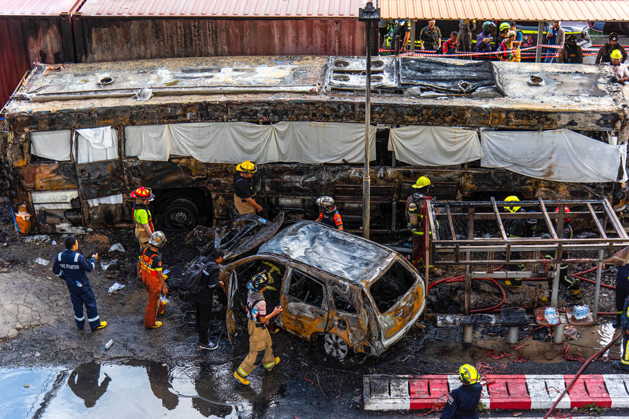 Rescue workers extinguish a fire on the wreckage of a public bus after it collides with a cargo train at the Makkasan airport rail link station. At least 8 people were killed and more than 25 people injured in the accident.