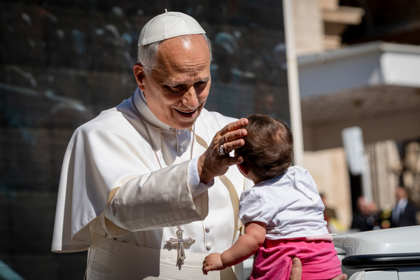Pope Leo XIV blesses a child as he arrives to lead his traditional Wednesday General Audience in St. Peter's Square in Vatican City.