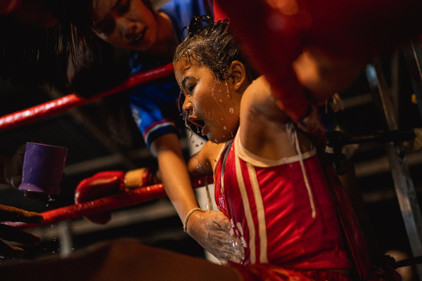 A young Muay Thai fighter is splashed with water during a break between rounds at a local boxing stadium in Ubon Ratchathani. In rural northeastern Thailand, Muay Thai is more than a sport, it is tradition, discipline, and sometimes a source of income for families. Among them, a growing number of young girls are making their mark in a world long shaped by men, balancing childhood, ambition, and family expectations both inside and outside the ring.