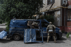 A police officer stands next to a van damaged by a drone during the evacuation of civilians by the Ukrainian police unit ‘White Angels’.