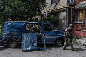 A police officer stands next to a van damaged by a drone during the evacuation of civilians by the Ukrainian police unit ‘White Angels’.