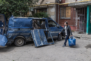 A man seen walking with his belongings in front of a vehicle damaged by a Russian FPV drone during an evacuation of civilians carried out by the Ukrainian police unit ‘White Angels’.