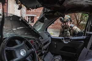A police officer seen standing next to a van damaged by a drone during the evacuation of civilians by the Ukrainian police unit ‘White Angels’ .