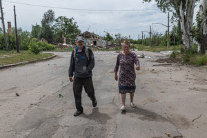 Civilians seen walking along a street damaged by Russian bombing.