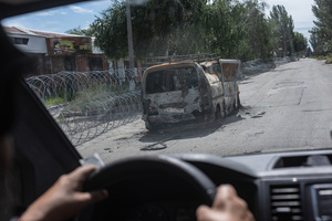 A burnt-out vehicle seen on the road following a strike by a Russian FPV drone during an evacuation operation by the Ukrainian police unit ‘White Angels’.