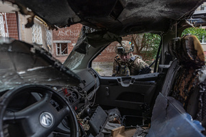 A police officer stands next to a van damaged by a drone during the evacuation of civilians by the Ukrainian police unit ‘White Angels’.