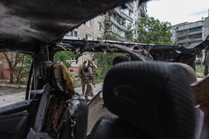 A police officer stands next to a van damaged by a drone during the evacuation of civilians by the Ukrainian police unit ‘White Angels’.
