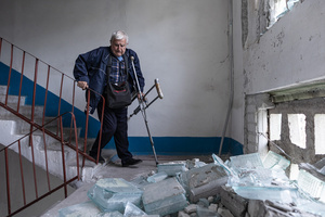 A man seen walking down the stairs of his home which has been damaged by Russian shelling during the evacuation of civilians by the ‘White Angels’ police unit.