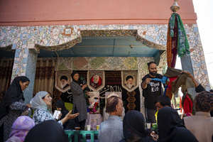 A Kashmiri Shia Muslim man ties a scarf to an Alam, a ceremonial flag associated with Muharram observances, during a procession commemorating the martyrdom of Imam Hussain and his companions in the Battle of Karbala. Muharram is the first month of the Islamic calendar. Shia Muslims observe Muharram as a period of mourning to commemorate the martyrdom of Imam Hussain, the grandson of Prophet Muhammad. Imam Hussain was martyred on the 10th day of Muharram, during the historic Battle of Karbala in 680 CE.