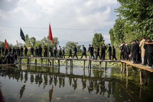 Shia Muslim mourners walk across a wooden bridge over Dal Lake during a Muharram procession commemorating the martyrdom of Imam Hussain and his companions in the Battle of Karbala. The procession forms part of annual mourning observances during the Islamic month of Muharram. Muharram is the first month of the Islamic calendar. Shia Muslims observe Muharram as a period of mourning to commemorate the martyrdom of Imam Hussain, the grandson of Prophet Muhammad. Imam Hussain was martyred on the 10th day of Muharram, during the historic Battle of Karbala in 680 CE.