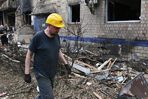 A utility worker walks near a residential building damaged during a missile strike. Following a devastating overnight bombardment in which Russia launched 74 missiles and 496 attack drones, Kyiv has declared July 3, 2026, a city-wide Day of Mourning to honor the victims. At least 25 people were killed and over 80 injured across the capital as direct strikes heavily damaged residential apartment blocks, leaving active search and rescue operations scrambling to locate residents still believed to be trapped under the rubble.