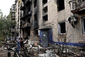 Local residents seen near a residential building, damaged during a missile strike. Following a devastating overnight bombardment in which Russia launched 74 missiles and 496 attack drones, Kyiv has declared July 3, 2026, a city-wide Day of Mourning to honor the victims. At least 25 people were killed and over 80 injured across the capital as direct strikes heavily damaged residential apartment blocks, leaving active search and rescue operations scrambling to locate residents still believed to be trapped under the rubble.