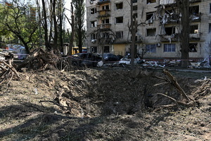 A massive crater marks the impact site of a missile near a residential apartment building. Following a devastating overnight bombardment in which Russia launched 74 missiles and 496 attack drones, Kyiv has declared July 3, 2026, a city-wide Day of Mourning to honor the victims. At least 25 people were killed and over 80 injured across the capital as direct strikes heavily damaged residential apartment blocks, leaving active search and rescue operations scrambling to locate residents still believed to be trapped under the rubble.