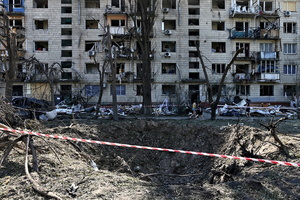 A massive crater marks the impact site of a missile near a residential apartment building. Following a devastating overnight bombardment in which Russia launched 74 missiles and 496 attack drones, Kyiv has declared July 3, 2026, a city-wide Day of Mourning to honor the victims. At least 25 people were killed and over 80 injured across the capital as direct strikes heavily damaged residential apartment blocks, leaving active search and rescue operations scrambling to locate residents still believed to be trapped under the rubble.