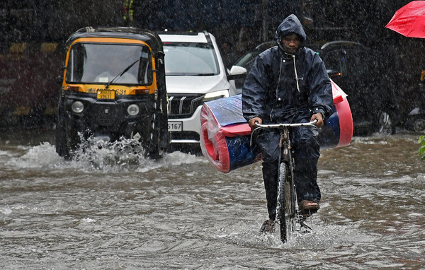 A man rides a bicycle on a flooded street after a heavy rain in Mumbai. Heavy rains battered the city flooding the streets. Indian Meteorological Department (IMD) has issued a red alert warning of extremely heavy rain for the weekend warning citizens not to venture out unless urgent.