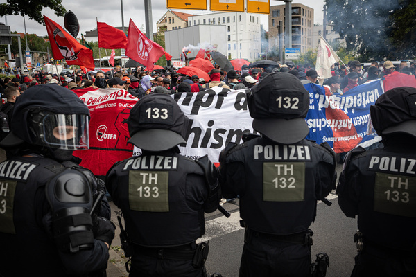 Police officers watch protesters holding placards during the demonstration against the federal party conference of the Alternative for Germany (AfD). The party’s two-day convention is being held at the Erfurt Exhibition Centre on July 4–5. According to police, around 31,000 people took part in the protests, while organizers estimated attendance at about 50,000. Demonstrators held marches, rallies and blockades of several access roads, including a section of the A71 motorway.