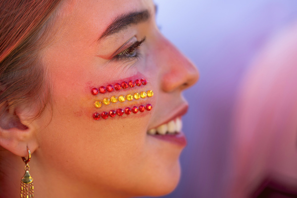A young Spanish football fan with red and yellow jewels on her cheek forming the national flag smiles during the team's World Cup victory parade. An estimated two million people flooded the capital's streets to welcome the squad following their 1-0 win against Argentina in the 2026 FIFA World Cup final.