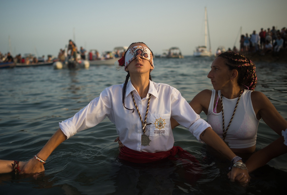 A blindfolded penitent of 'Virgen del Carmen' brotherhood is seen in the water as she takes part in a procession at the beach. The annual 'Virgen del Carmen' festivity in Málaga City, held on 16 July, celebrates the patron saint of sailors and fishermen. The statue of the Virgin is carried by a group of believers in traditional costume along the streets before being placed on a boat from a beach, which later sails down the Málaga coast.