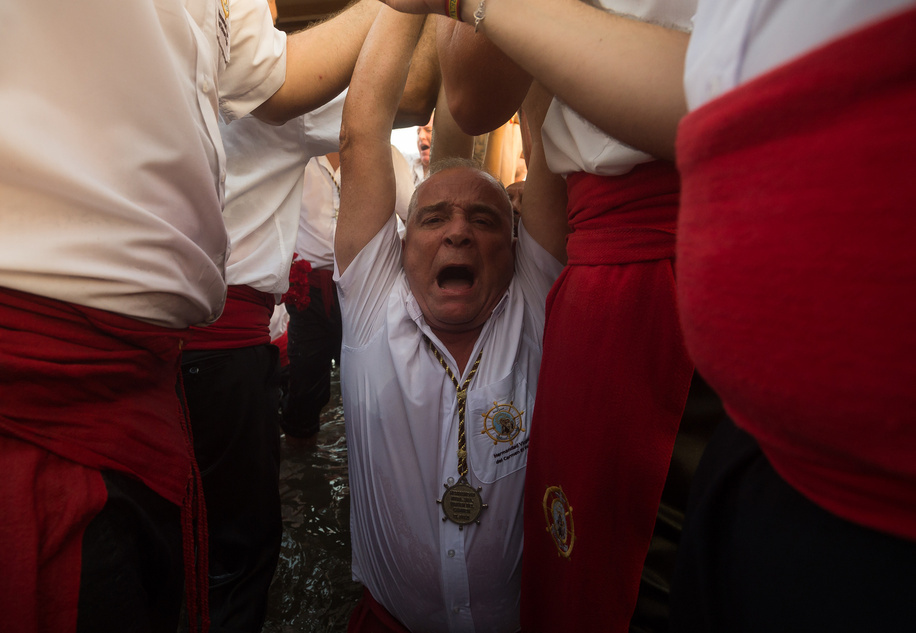 A penitent of 'Virgen del Carmen' brotherhood is seen kneeling in the water as he takes part in a procession at a beach. The annual 'Virgen del Carmen' festivity in Málaga City, held on 16 July, celebrates the patron saint of sailors and fishermen. The statue of the Virgin is carried by a group of believers in traditional costume along the streets before being placed on a boat from a beach, which later sails down the Málaga coast.