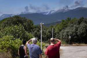 People watch as a massive column of smoke rises from a wildfire burning in Ávila. The fire has triggered an extreme fire danger alert across central Spain, including Madrid and neighboring regions.