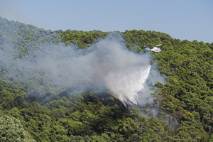 A firefighting helicopter drops water on a forest fire in Ávila as emergency crews work to contain the blaze. The wildfire has prompted an extreme fire danger alert across central Spain including Madrid and surrounding regions.