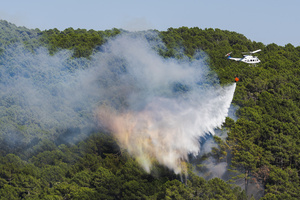A firefighting helicopter drops water on a forest fire in Ávila as emergency crews work to contain the blaze. The wildfire has prompted an extreme fire danger alert across central Spain including Madrid and surrounding regions.
